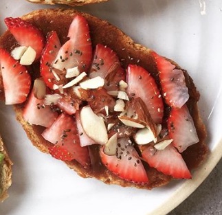 A piece of toast with strawberries and almonds on it.